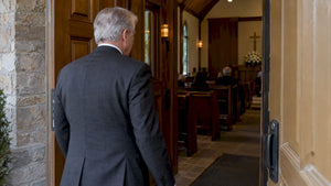 Mourner in a dark suit at chapel entrance