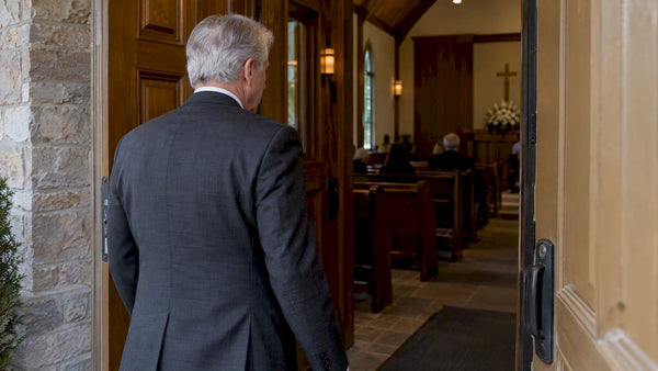 Mourner in a dark suit at chapel entrance