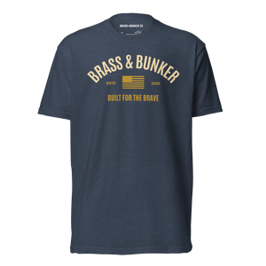 A navy blue heather crewneck t-shirt with a vintage-style graphic on the chest reading 'BRASS & BUNKER' in cream, featuring a small American flag and 'BUILT FOR THE BRAVE' text below.