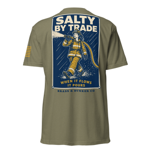An olive green short-sleeve t-shirt shown from the back, featuring a large graphic print of a firefighter with the text 'SALTY BY TRADE' and 'BRASS & BUNKER CO'.