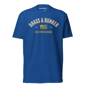 A royal blue short-sleeve crewneck t-shirt with a yellow graphic on the chest reading 'BRASS & BUNKER' and 'BUILT FOR THE BRAVE' with a small American flag design.