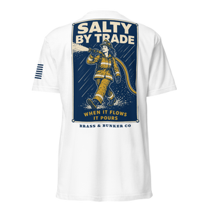 White short-sleeve t-shirt shown from the back, featuring a large graphic print of a firefighter in yellow gear on a dark blue background with the text 'SALTY BY TRADE' and 'BRASS & BUNKER CO'. A small navy stripe graphic is visible on the right sleeve.